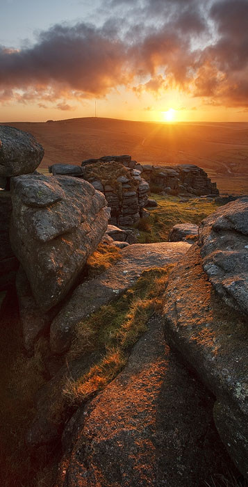 the sun rises over Staple Tor with granite lit up in the foreground.