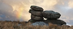 A rainbow forms next to Black Tor on Dartmoor