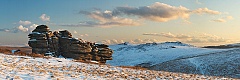 crow tor in the snow with the beardown tors in the distance shot at sunset