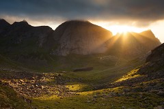 sunrays burst over a ridge in Lofoten Norway