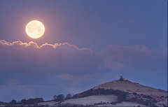 the moon setting at sunrise next to Brentor Church in Devon
