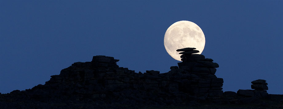 the moon rises behind Staple Tor