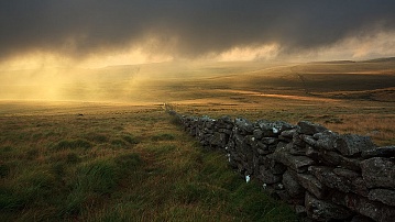 sun breaks thoguh in the distance on Dartmoor with dark clouds overhead