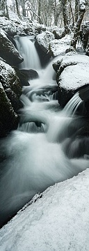 a waterfall in the winter surrounded by snow in Deovn